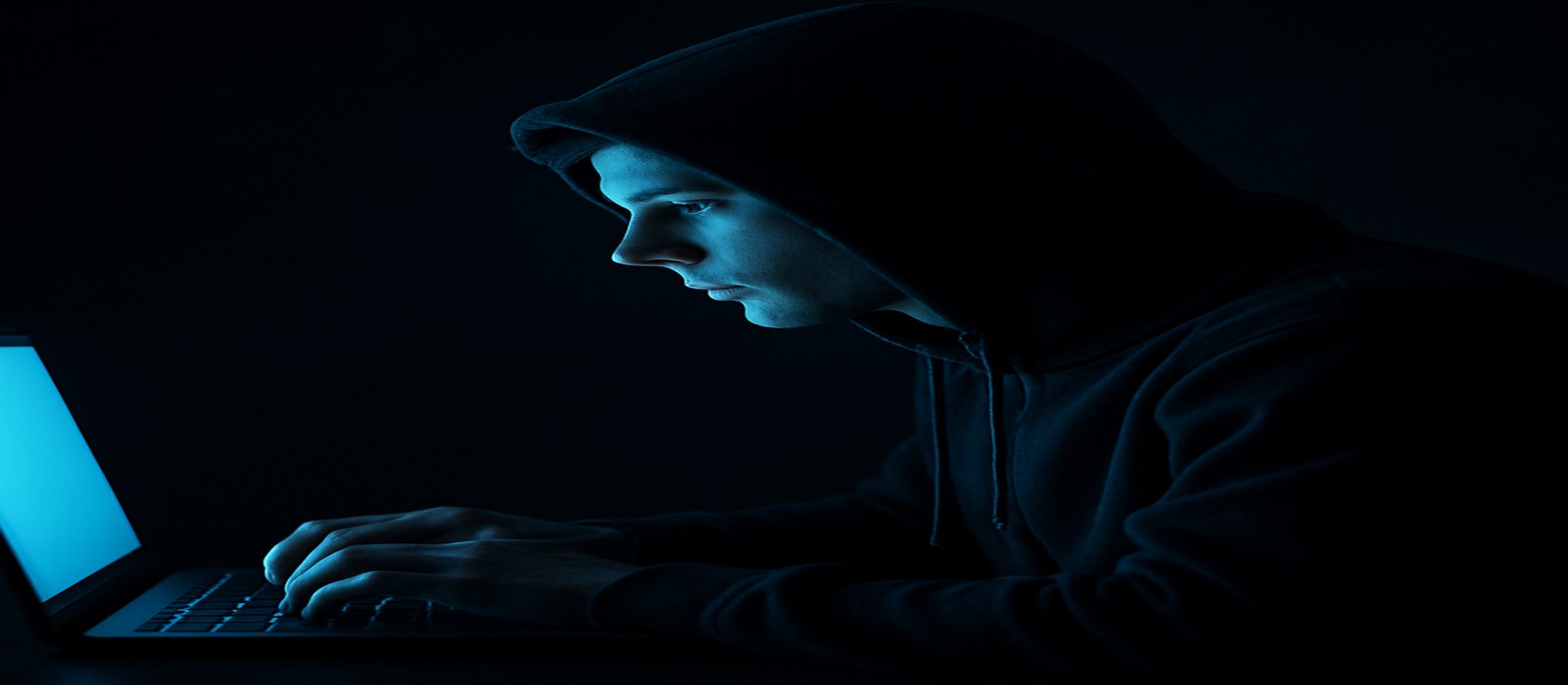 একজন ব্যক্তি অন্ধকার একটি কক্ষে ল্যাপটপ সামনে রেখে tk33 ওয়েবসাইটে অনলাইন গেম খেলার জন্য পুরো মনোযোগ দিচ্ছেন